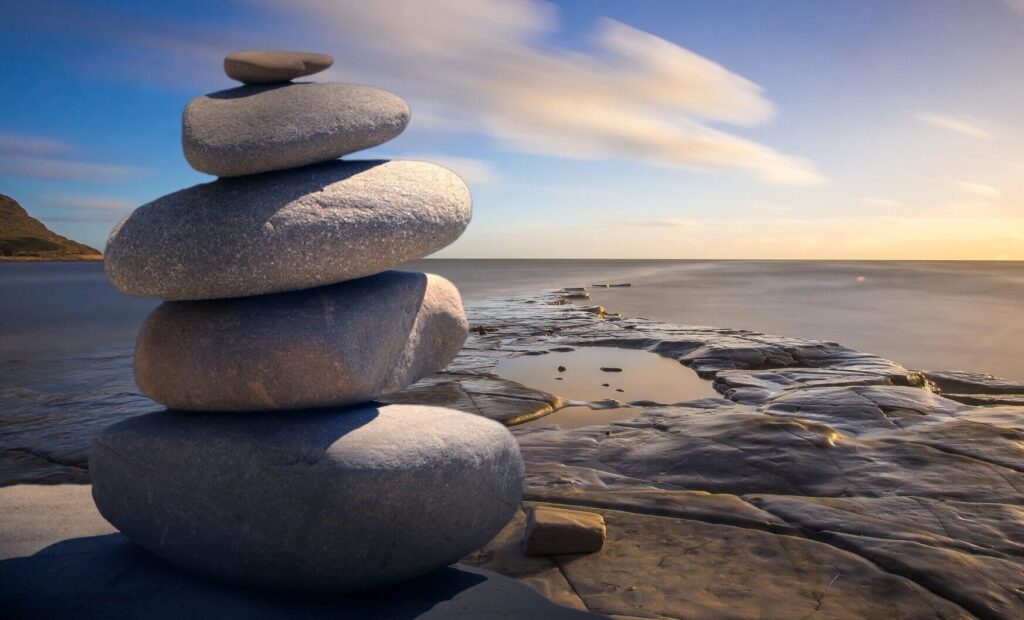 A beautiful ocean view and stones stack on each other - Real Life Chiropractic in Salt Lake City UT