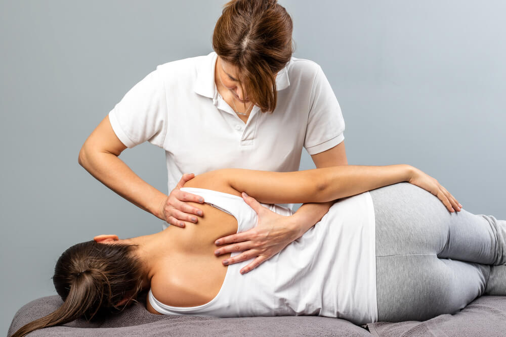 Physiotherapist examining leg injury on a woman lying down - Real Life Chiropractic in Salk Lake city UT