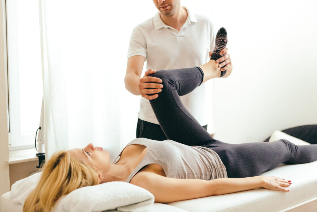 Physiotherapist examining leg injury on a woman lying down - Real Life Chiropractic in Salk Lake city UT